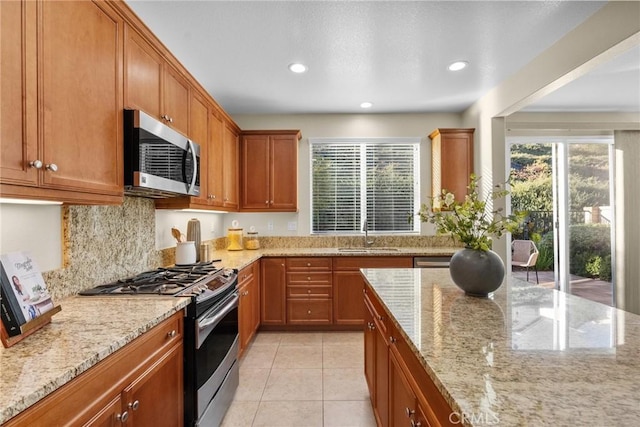 kitchen featuring light stone counters, stainless steel appliances, light tile patterned floors, decorative backsplash, and sink