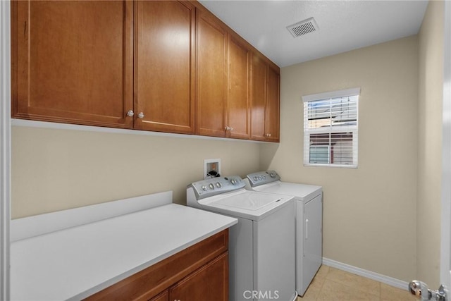 clothes washing area with washing machine and dryer and cabinets