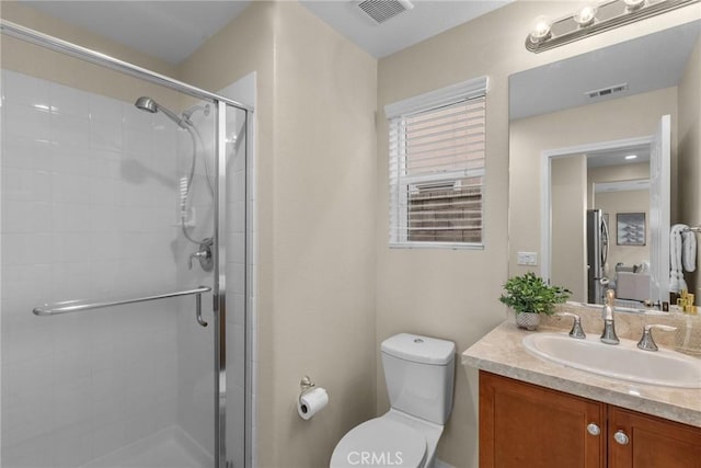 bathroom with a shower with door, vanity, and toilet