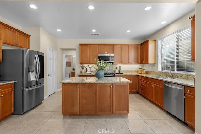 kitchen featuring a kitchen island, appliances with stainless steel finishes, light stone counters, and sink