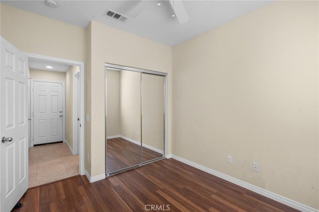 unfurnished bedroom with dark wood-type flooring, ceiling fan, and a closet