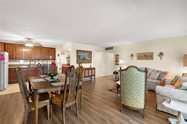 dining area with a textured ceiling, light hardwood / wood-style flooring, and ceiling fan