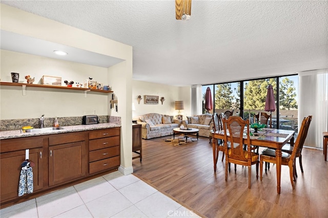 dining space featuring sink, a textured ceiling, light hardwood / wood-style flooring, and a wall of windows