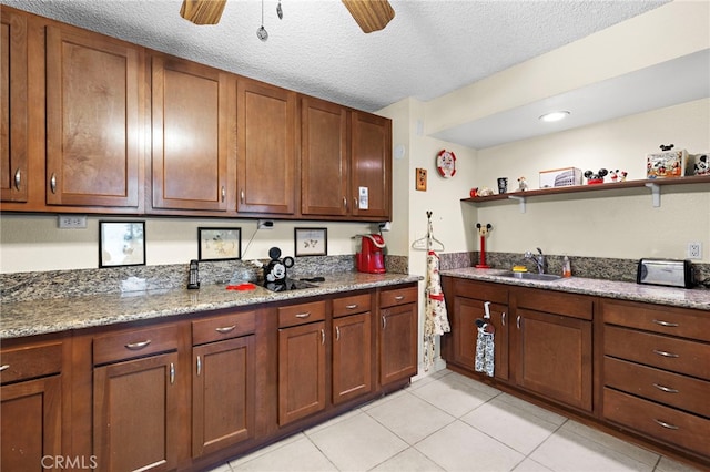 kitchen featuring a textured ceiling, light tile patterned floors, sink, ceiling fan, and light stone counters