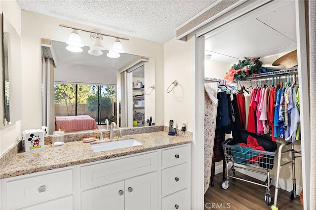 24055 Paseo Del Lago Unit 103, Laguna Woods, CA 92637 - ensuite bathroom with a walk in closet, vanity, wood finished floors, and a textured ceiling