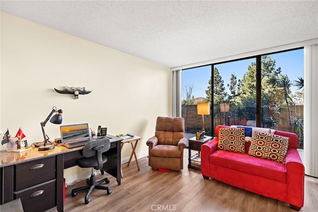 home office featuring hardwood / wood-style flooring, a textured ceiling, floor to ceiling windows, and plenty of natural light