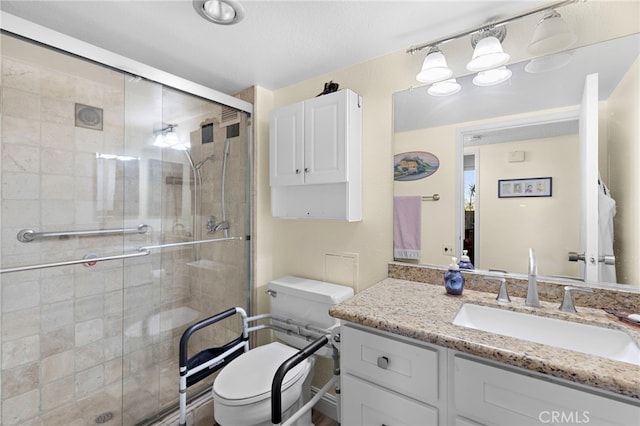 bathroom featuring toilet, a shower with shower door, and vanity