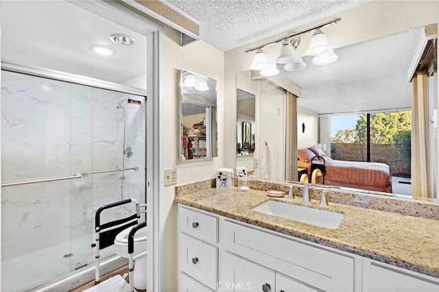 bathroom featuring a textured ceiling, a shower with shower door, and vanity