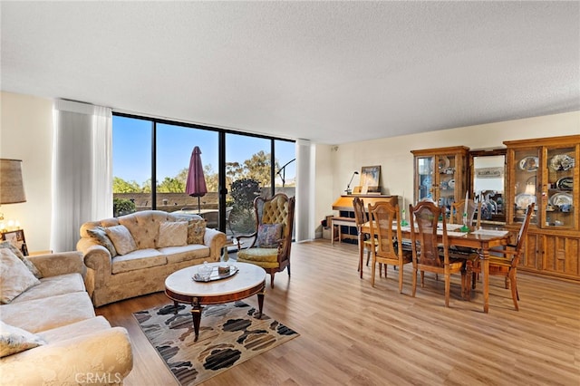 living room with floor to ceiling windows, a textured ceiling, and light wood-type flooring