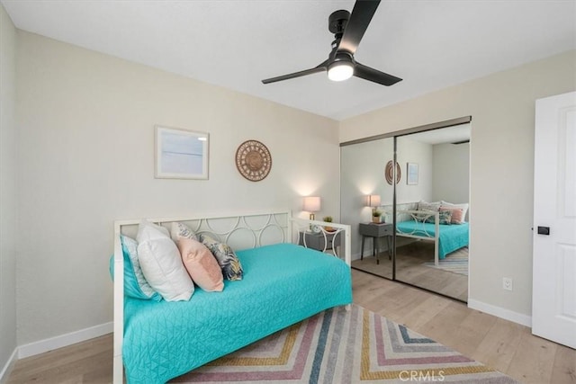 bedroom with light wood-type flooring, ceiling fan, and a closet