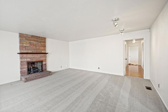 unfurnished living room featuring light carpet and a stone fireplace