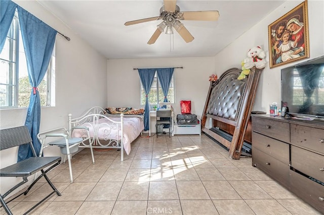 bedroom featuring ceiling fan, light tile patterned floors, and multiple windows