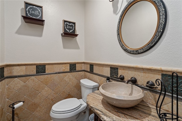 bathroom featuring tile walls, toilet, and sink