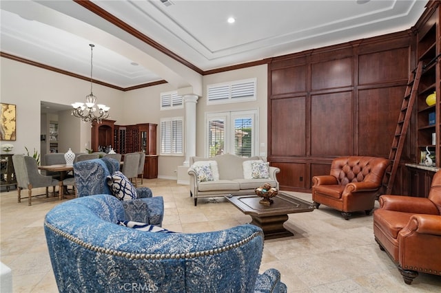 living room with a towering ceiling, an inviting chandelier, crown molding, and ornate columns