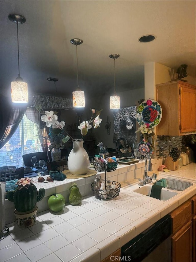 kitchen with sink, pendant lighting, tile countertops, and stainless steel dishwasher