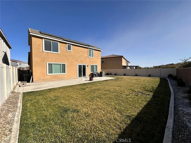 rear view of house featuring a yard, a patio area, and solar panels