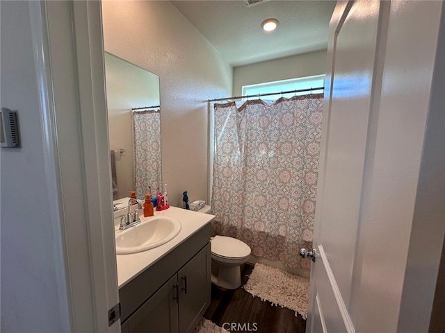 full bathroom featuring hardwood / wood-style flooring, vanity, toilet, and shower / tub combo