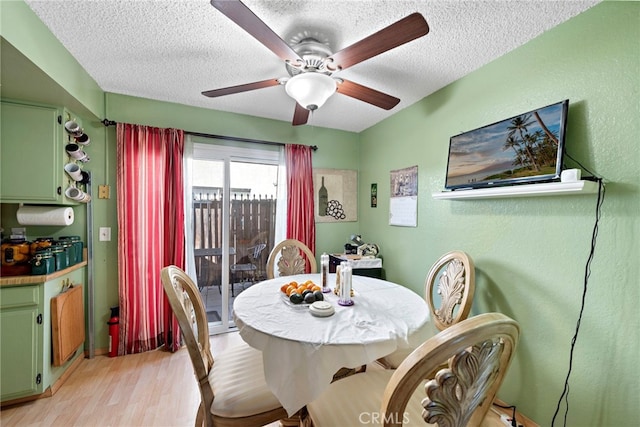 dining room with light hardwood / wood-style floors, ceiling fan, and a textured ceiling