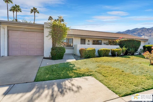 ranch-style home with a front yard, a garage, and a mountain view