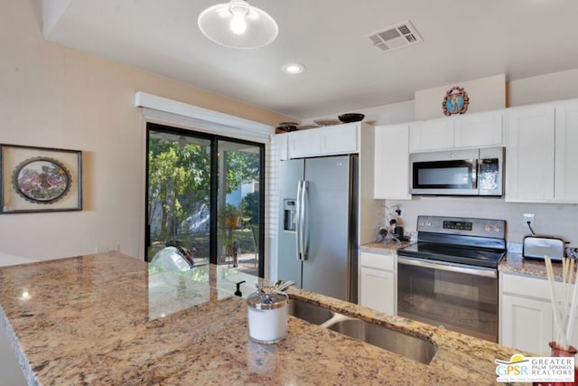 kitchen with stainless steel appliances, light stone countertops, and white cabinets