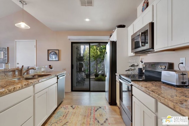 kitchen featuring light stone counters, appliances with stainless steel finishes, pendant lighting, and white cabinetry