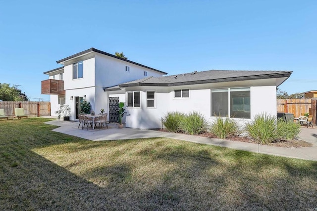 rear view of property featuring a balcony, a yard, and a patio area