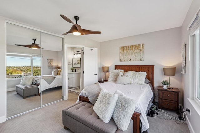 bedroom featuring a closet, ensuite bathroom, light carpet, and ceiling fan