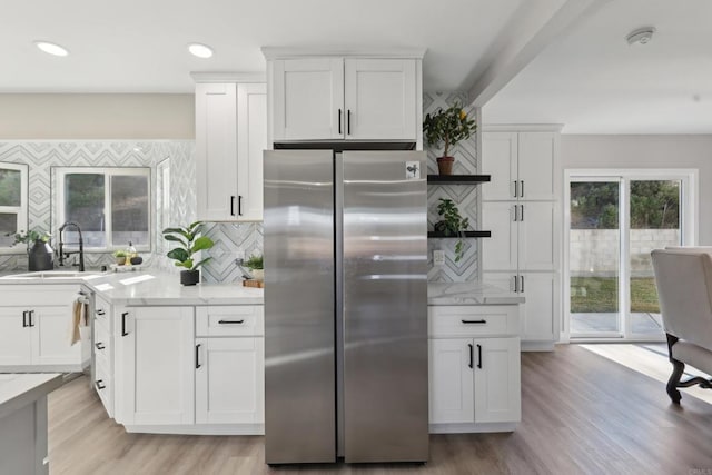 kitchen with light hardwood / wood-style flooring, white cabinetry, decorative backsplash, and stainless steel refrigerator