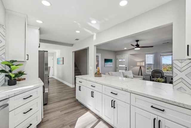 kitchen with ceiling fan, appliances with stainless steel finishes, light stone counters, light hardwood / wood-style floors, and white cabinets