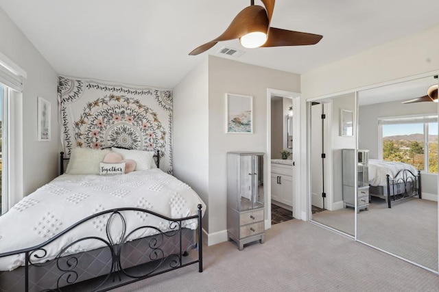 bedroom with ceiling fan, a closet, connected bathroom, and light carpet