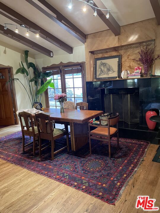 dining space featuring wood-type flooring and beamed ceiling