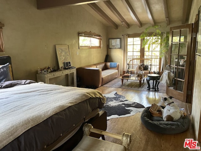 bedroom featuring light hardwood / wood-style flooring and vaulted ceiling with beams