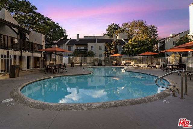 pool at dusk featuring a patio area