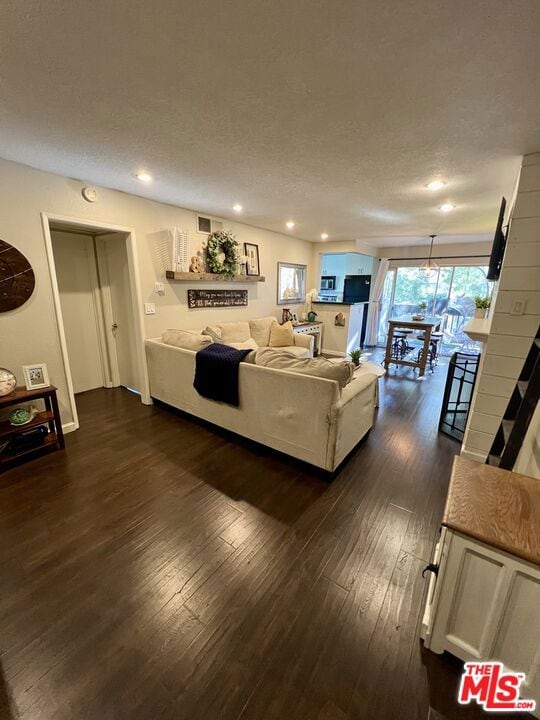 living room with a textured ceiling and dark hardwood / wood-style flooring