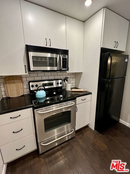 kitchen with white cabinetry, dark wood-type flooring, tasteful backsplash, and appliances with stainless steel finishes