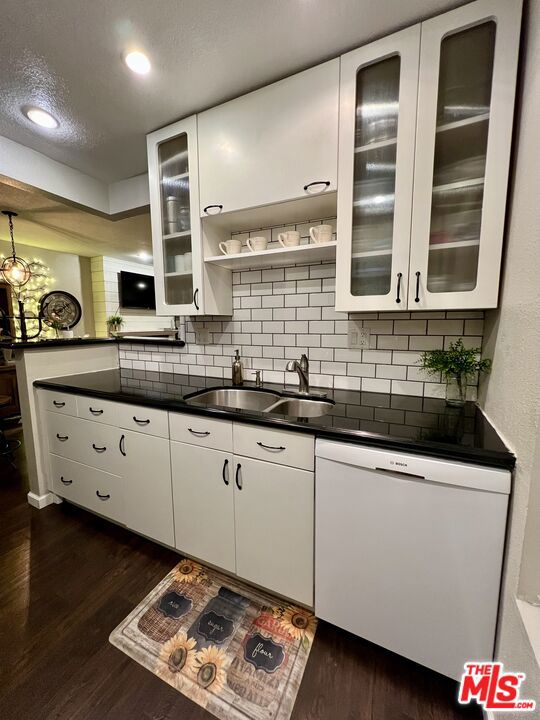 kitchen with sink, white dishwasher, white cabinets, and dark wood-type flooring