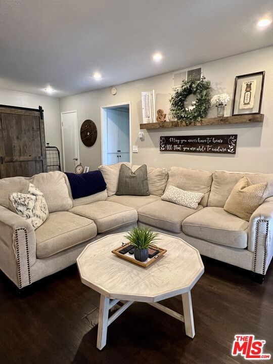 living room with dark wood-type flooring and a barn door