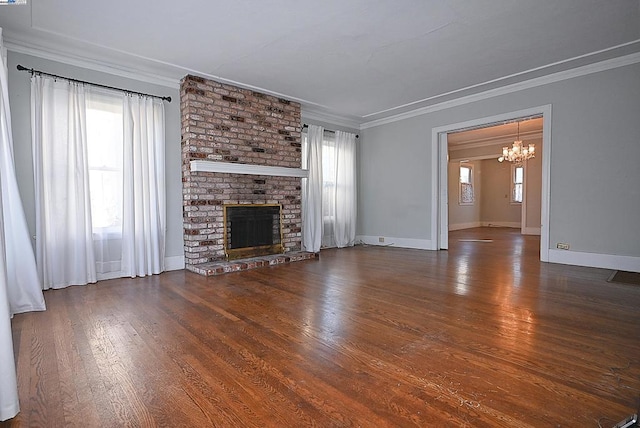 unfurnished living room with a fireplace, dark wood-type flooring, ornamental molding, and a chandelier