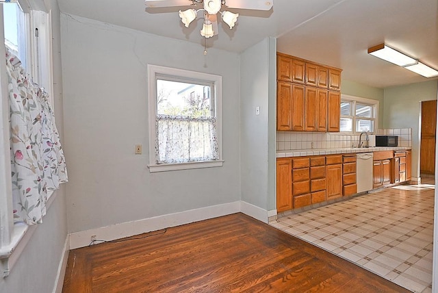 kitchen featuring dishwasher, light hardwood / wood-style floors, ceiling fan, sink, and tasteful backsplash