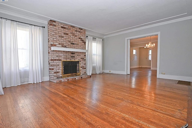 unfurnished living room with a notable chandelier, a brick fireplace, and ornamental molding