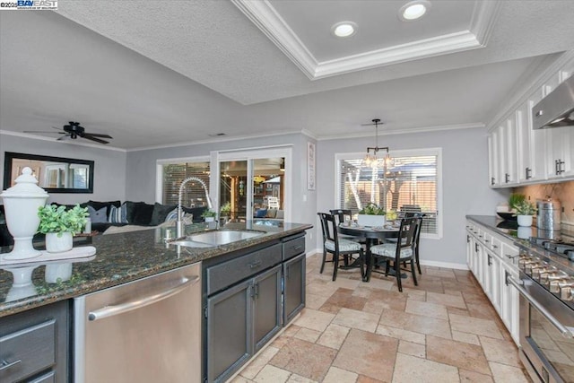 kitchen featuring sink, white cabinetry, hanging light fixtures, dark stone countertops, and stainless steel appliances