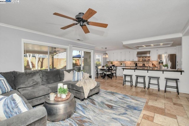 living room with crown molding, ceiling fan, and a wealth of natural light