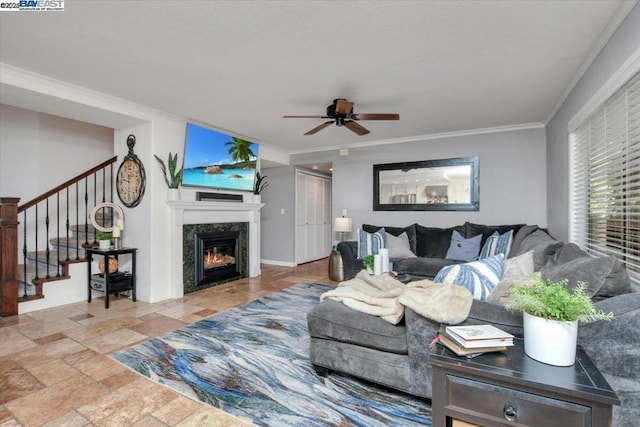 living room featuring ceiling fan, ornamental molding, and a fireplace