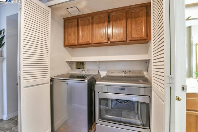 clothes washing area with washing machine and dryer and cabinets