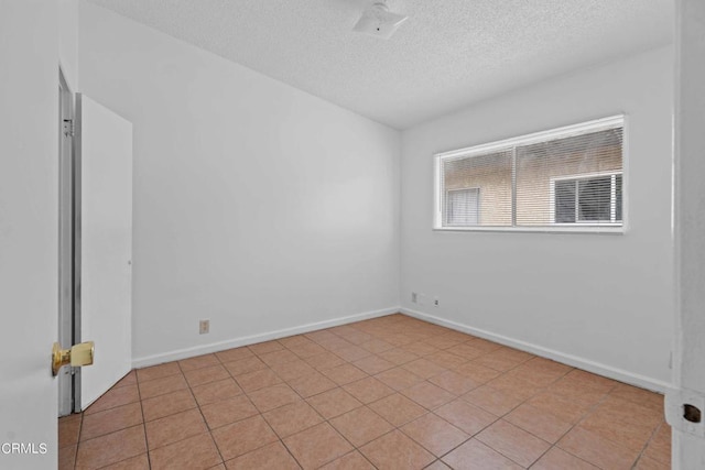 tiled spare room featuring a textured ceiling