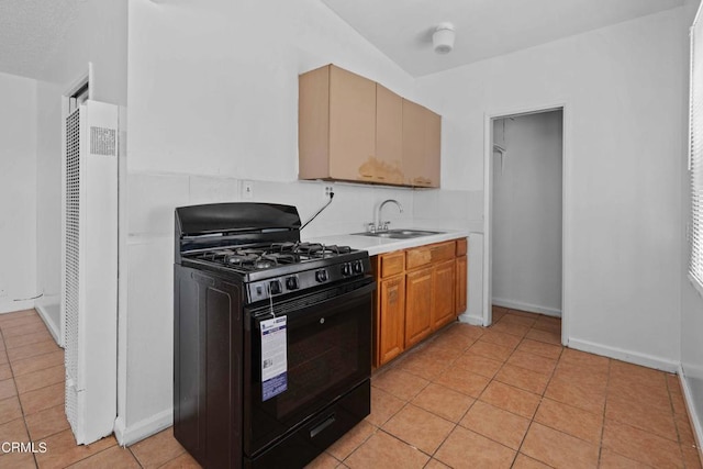 kitchen featuring gas stove, light tile patterned flooring, and sink