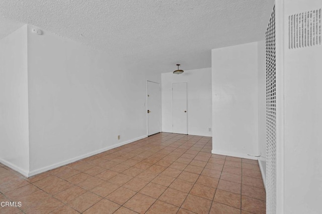 empty room featuring a textured ceiling and light tile patterned floors