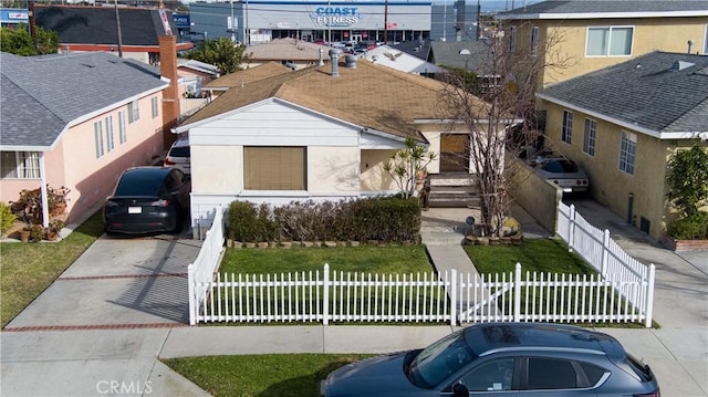 view of front of home with roof with shingles, a fenced front yard, and stucco siding