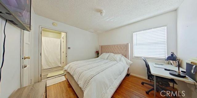 bedroom featuring dark wood-type flooring, a textured ceiling, and baseboards