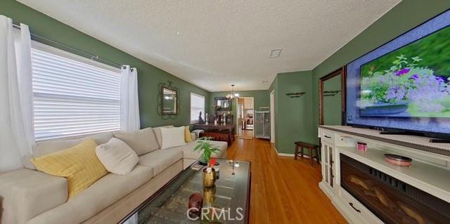 living room featuring an inviting chandelier, a textured ceiling, and wood finished floors